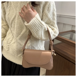 Detail of a beige crescent-shaped leather shoulder bag with knotted strap design