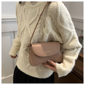 Detail of wave-shaped base on beige crossbody bag with gold fashion lettering