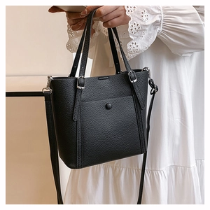 Close-up of black litchi pattern leather tote bag with silver hardware and shoulder strap