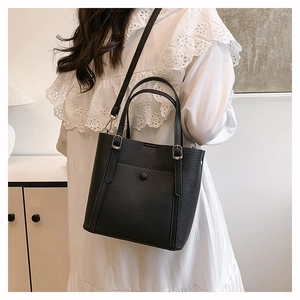 Close-up of black lychee grain leather tote bag with silver snap button and shoulder strap