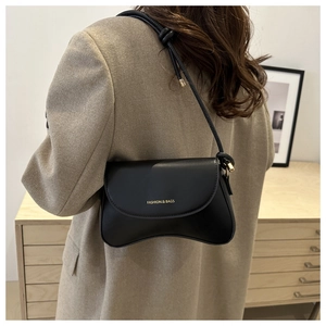 Detail of a black leather underarm bag with gold lettering and a stylish knotted strap