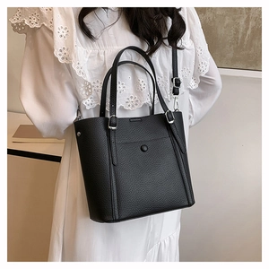 Detail of black lychee grain leather tote bag worn by model with adjustable strap