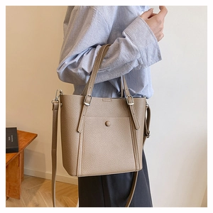 Detail of khaki pebbled leather tote with functional front pocket and silver hardware