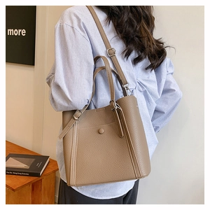 Detailed close-up of brown lychee grain leather texture and handle strap on tote bag