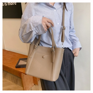 Close-up of khaki pebbled leather tote bag with front pocket and adjustable straps