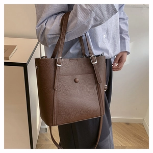 Detail view of brown pebbled leather tote bag with silver buckle and adjustable straps