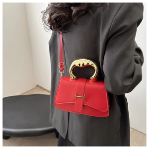 Detail der roten Lederbox-Tasche mit goldener H-Schnalle und Metallgriff am Modell