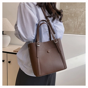 Detail of dark brown leather tote bag showing lychee grain texture and metal buckle