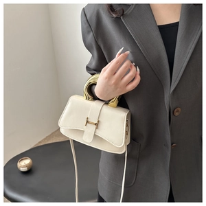 Detailansicht der cremeweißen Lederhandtasche mit goldenem Bogengriff und Metallverschluss