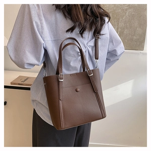 Detail of dark brown litchi pattern leather tote bag with handle and shoulder strap