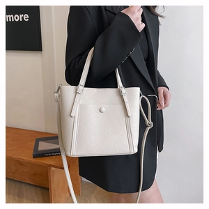 Detail of white lychee pattern tote bag with round buckle and adjustable strap on model