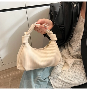 Détail du sac à main plissé crème avec poignée à nœuds symétriques et fermeture éclair