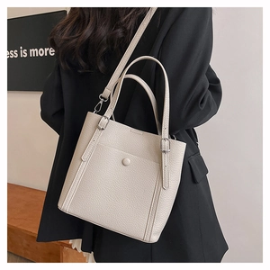 Close-up of off-white lychee leather tote bag with silver buckle and adjustable shoulder strap