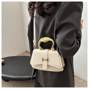 Detail der cremefarbenen Ledertasche mit goldenem Skulpturgriff und H-Verschluss