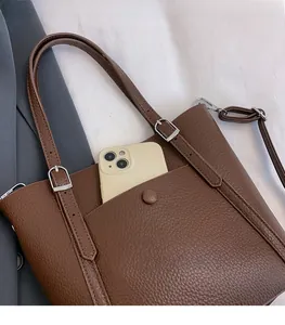 Detail of brown litchi pattern leather tote bag showing pocket with adjustable strap