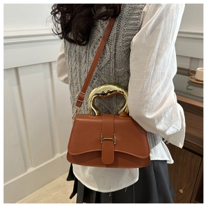 Braune Ledertasche mit goldenem Griff und Schnalle auf grau gestrickter Weste