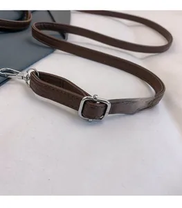 Close-up of brown leather strap with silver metal buckle and textured litchi grain finish