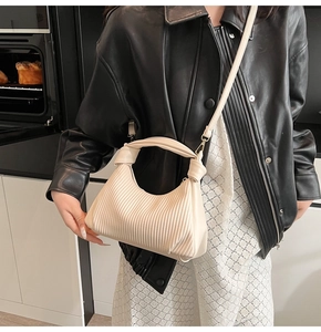 Sac à bandoulière plissé beige porté avec une veste en cuir et une jupe en dentelle