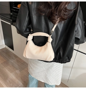 Détail du sac à main plissé crème avec plis en accordéon et finitions métalliques dorées
