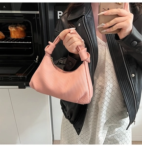 Détails d'un sac à main plissé rose montrant la texture plissée et l'anse nouée