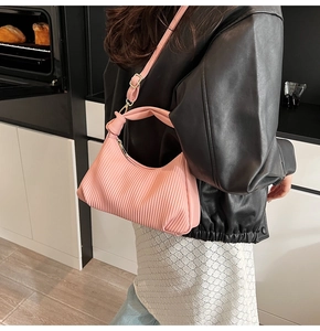 Détail du sac à main plissé rose avec bandoulière à nœud réglable et fini mat