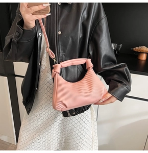 Détail du sac à main plissé rose avec poignée nouée et bandoulière amovible élégante
