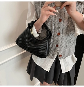 Détail du sac à bandoulière noir plissé avec poignée nouée et finition brillante