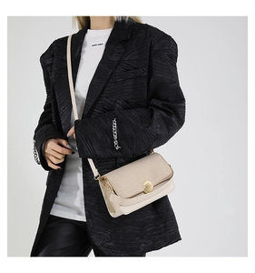 Detail of beige flap crossbody bag with golden metal buckle and fine glitter texture