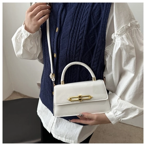 Detail of white glossy underarm bag featuring a modern gold rectangular swivel lock