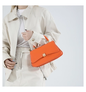 Dettaglio borsa a mano in pelle arancione vivace con texture premium e fibbia oro