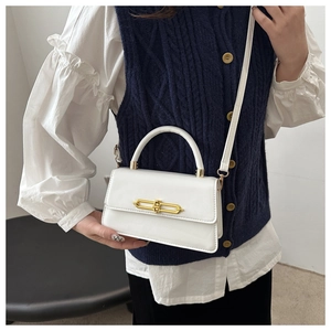 Detailed view of a white leather crossbody bag featuring a striking gold metal lock and strap
