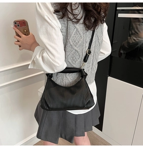 Détail du sac bandoulière noir plissé avec poignée souple et boucles en métal doré
