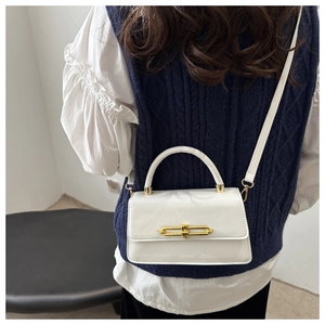 Close-up of white leather handbag with elegant gold metal clasp and top handle