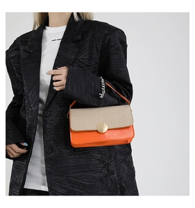 Detail of orange leather and beige woven fabric textures on an elegant crossbody bag
