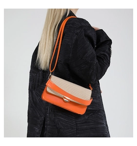 Detail of color-block crossbody bag with orange leather and beige woven fabric on model