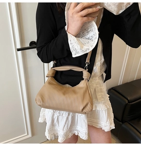 Vue détaillée du sac à bandoulière plissé beige avec poignée nouée et texture de cuir
