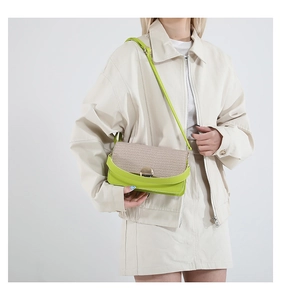 Detail of lime green faux leather and woven straw crossbody bag with golden metal buckle