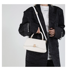 Detailed view of white minimalist square crossbody bag with gold buckle on a model