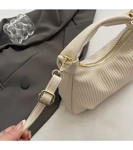 Gros plan d'un sac plissé beige avec crochet doré et détails de fermeture éclair en métal