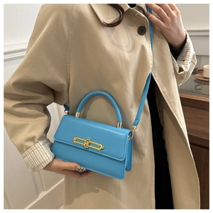 Detail of a bright blue PU leather handbag with elegant gold metal twist-lock buckle