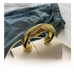 Detailansicht der weißen Ledertasche mit goldenem Metallgriff auf Denim-Hintergrund