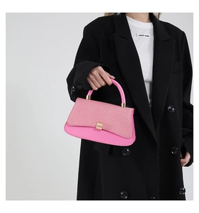 Detailed shot of pink woven baguette bag with gold metal buckle and contrast texture