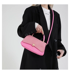 Pink textured handbag with gold clasp shown styled with a black blazer on a model