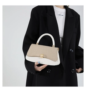 Detail of contrast stitch straw and white leather handbag with gold metal clasp