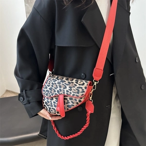 Sac selle léopard tendance avec bandoulière rouge et chaîne porté par un mannequin