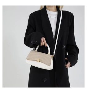 Detail of elegant two-tone leather handbag with woven texture and gold metallic lock