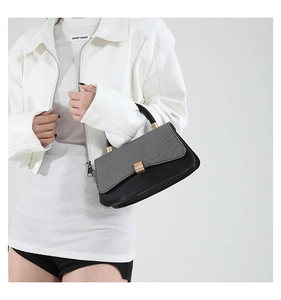 Detail of grey textured fabric and black leather contrast handbag with gold clasp