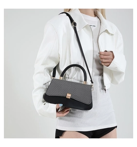 Detail showing contrast color crossbody bag with gold hardware and top handle on model