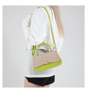 Detail of green handbag with woven texture flap and golden hardware on model