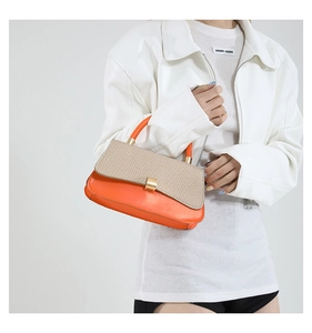 Detail of orange leather handbag with beige woven texture flap and golden lock